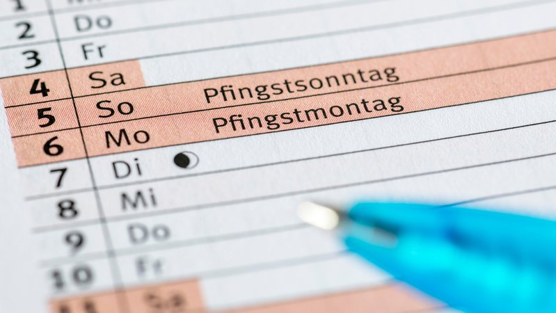 (Symbolbild) Ein Stift unter einem Monatskalender mit Fokus auf den Feiertagen zu Pfingsten. | Bild: picture alliance / imageBROKER | Lilly (Symbolbild) Ein Stift unter einem Monatskalender mit Fokus auf den Feiertagen zu Pfingsten.