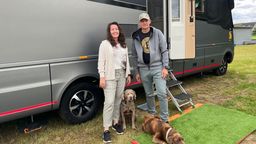 Das Ehepaar Melanie und Martin Ebert steht mit seinen beiden Hunden vor einen großen, grauen Wohnmobil.  | Bild:BR / Sandra Jozipovic