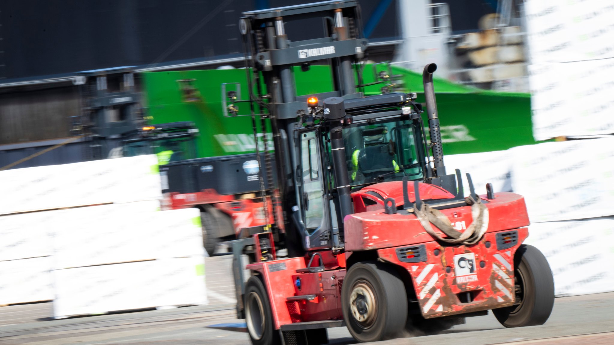Ein roter Gabelstapler transportiert ein grünes Eisenteil. | Bild: picture alliance/dpa | Philip Dulian Ein roter Gabelstapler transportiert ein grünes Eisenteil.