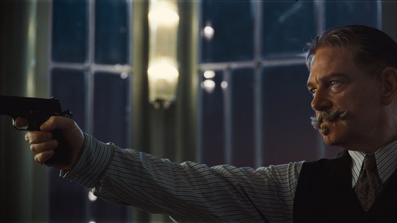 Kenneth Branagh als Meisterdetektiv Poirot mit Schnurrbart und Waffe.