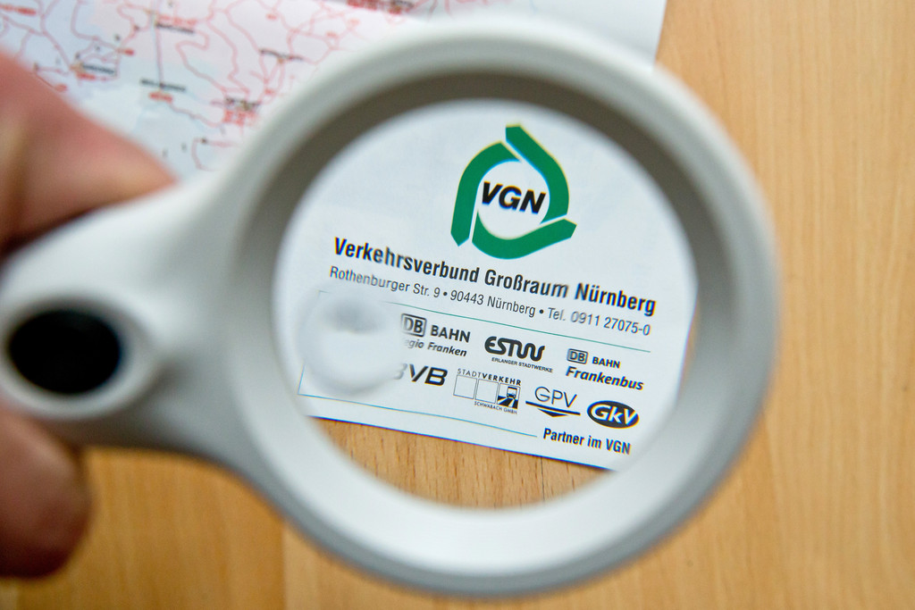Durch eine Lupe ist auf einer Karte vom aktuellen Gesamtraum des Verkehrsnetz vom Verkehrsverbund Großraum Nürnberg (VGN) das VGN-Logo zu sehen.