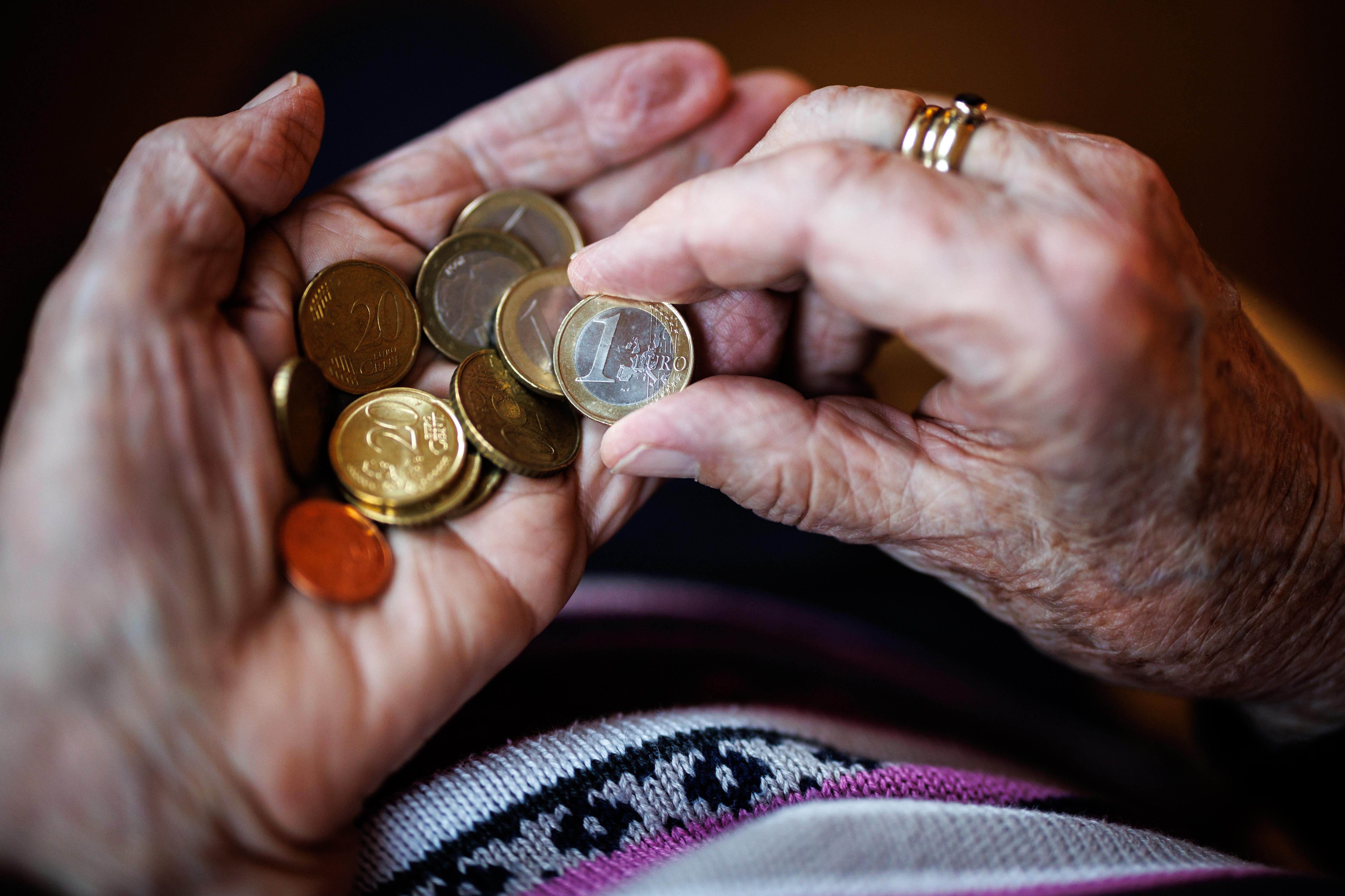 Eine ältere Dame zählt in ihren Händen das Bargeld aus ihrem Portemonnaie ab.  