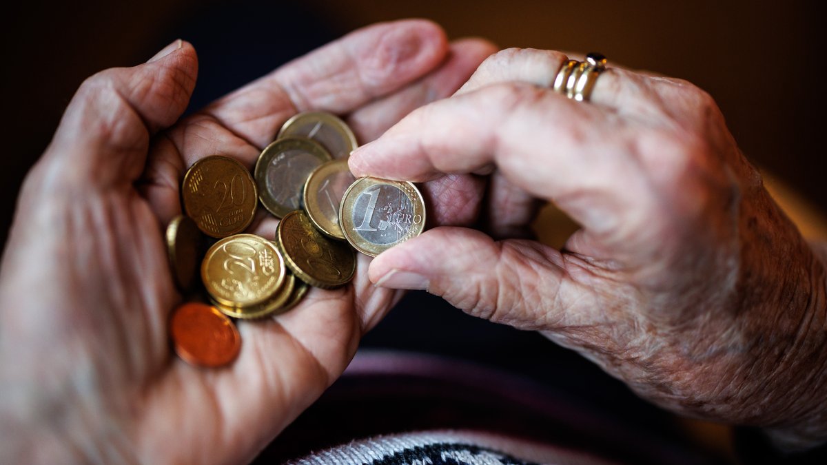 Eine ältere Dame zählt in ihren Händen das Bargeld aus ihrem Portemonnaie ab.  