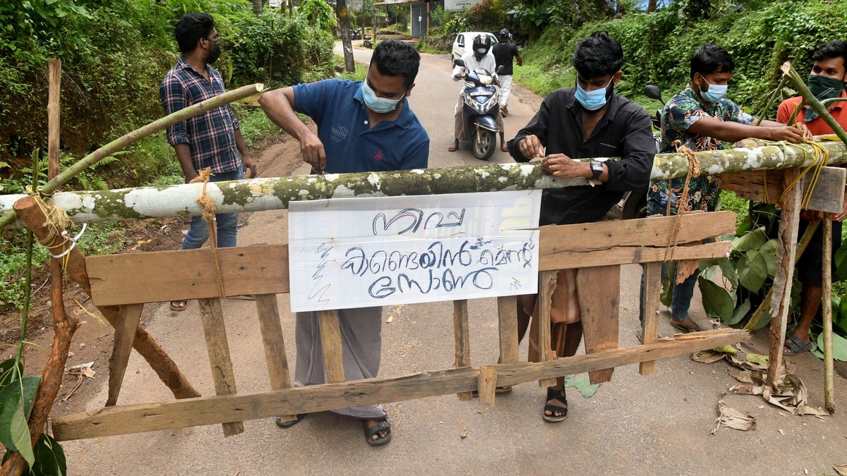 Anwohner befestigen ein Schild mit der Aufschrift "Nipah-Sperrzone" an einer Barrikade.