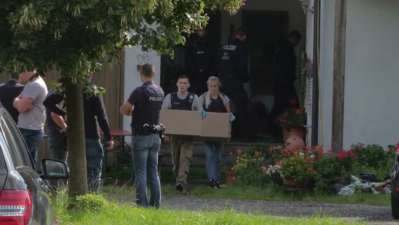 Polizisten tragen Kisten aus Gebäude | Bild: BR Polizisten tragen Kisten aus Gebäude