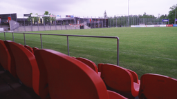 Man sieht die Sitze einer Zuschauertribüne und im Hintergrund den Fußballplatz | Bild:BR/Josef Schön