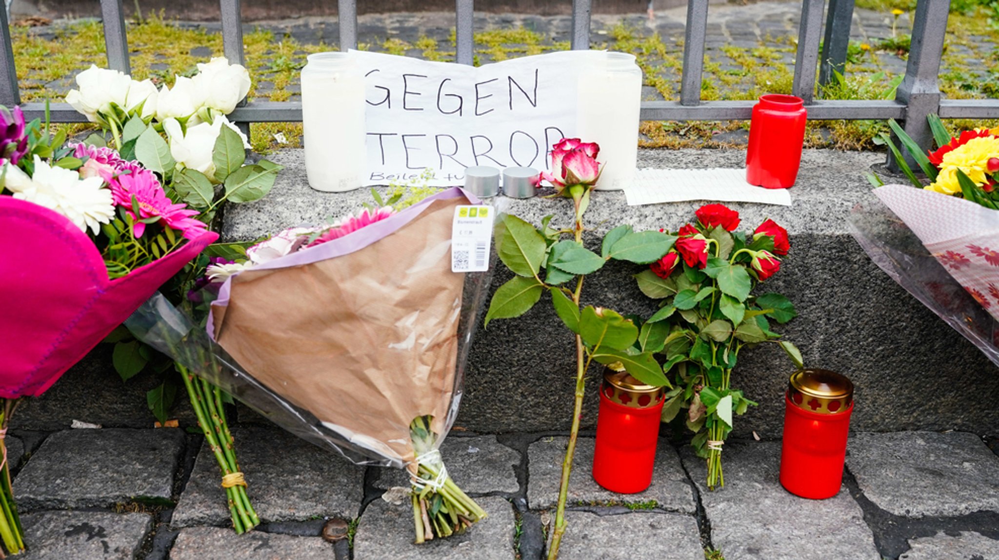 Kerzen, Blumen und ein Blatt Papier mit der Aufschrift ·Gegen Terror· stehen am Tatort auf dem Mannheimer Marktplatz. 