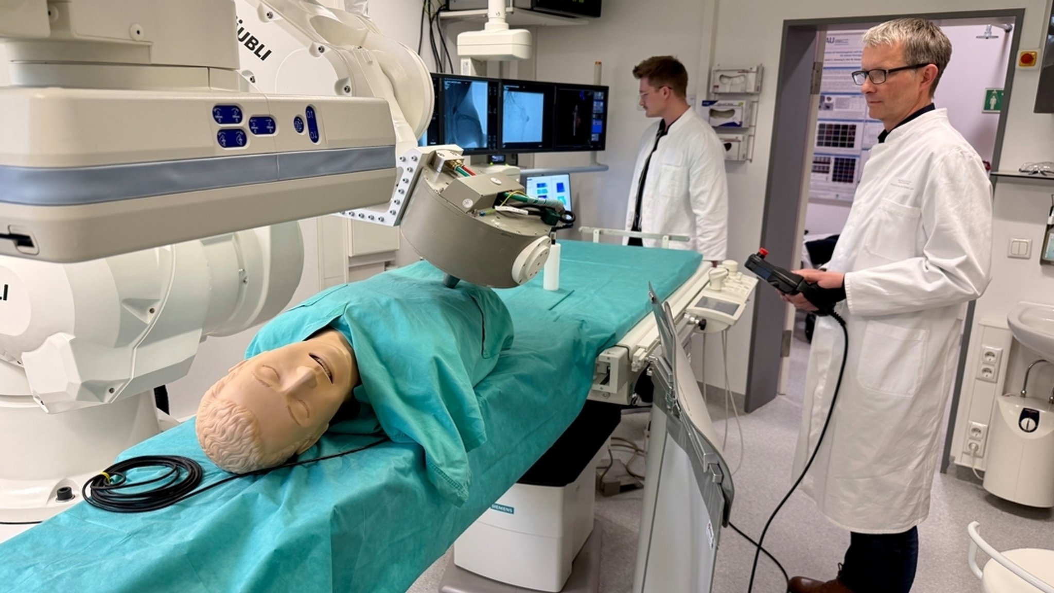 In einem Forschungslabor der Universität Erlangen präsentieren zwei Mitarbeiter an einer Puppe den Einsatz eines Magnetroboters für die Nanomedizin.