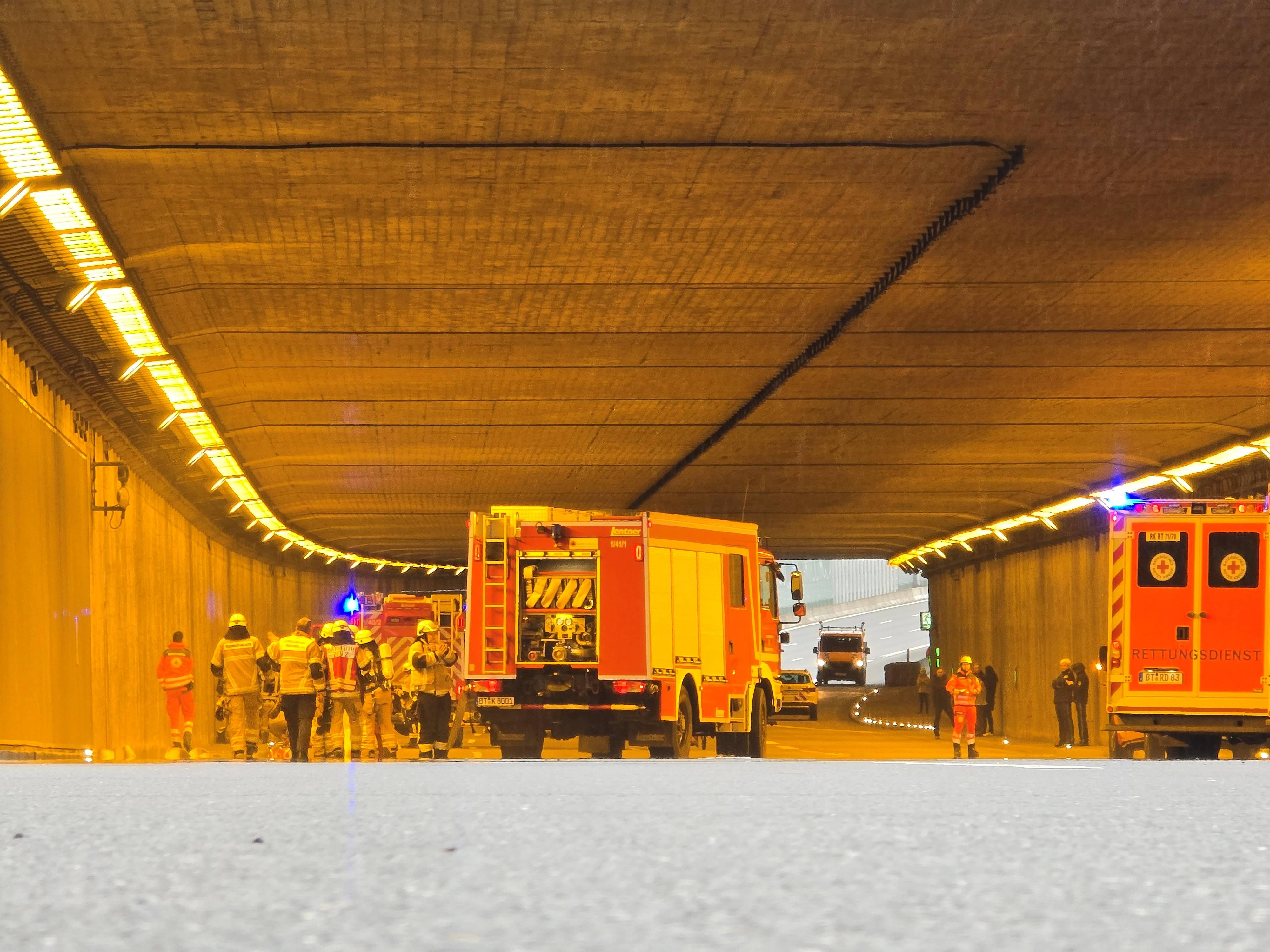 Rettungskräfte der Feuerwehr stehen samt Fahrzeugen in einem Tunnel bei Bayreuth.