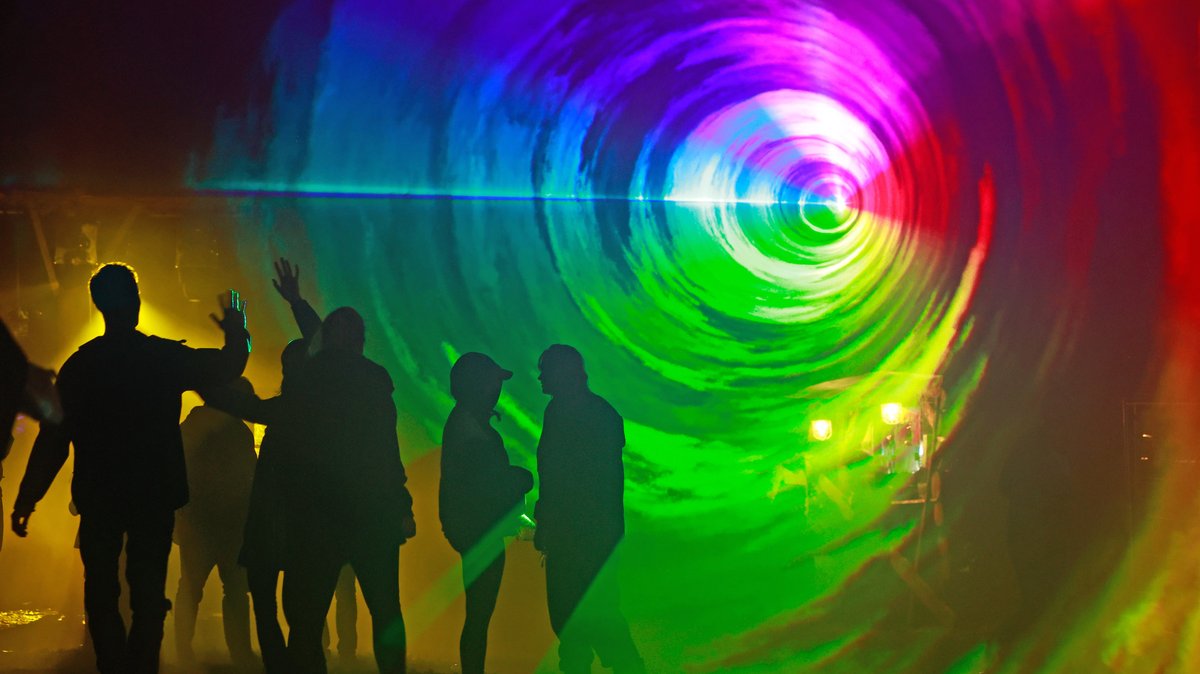 Tanzende Festival-Besucher vor buntem Laserlicht 