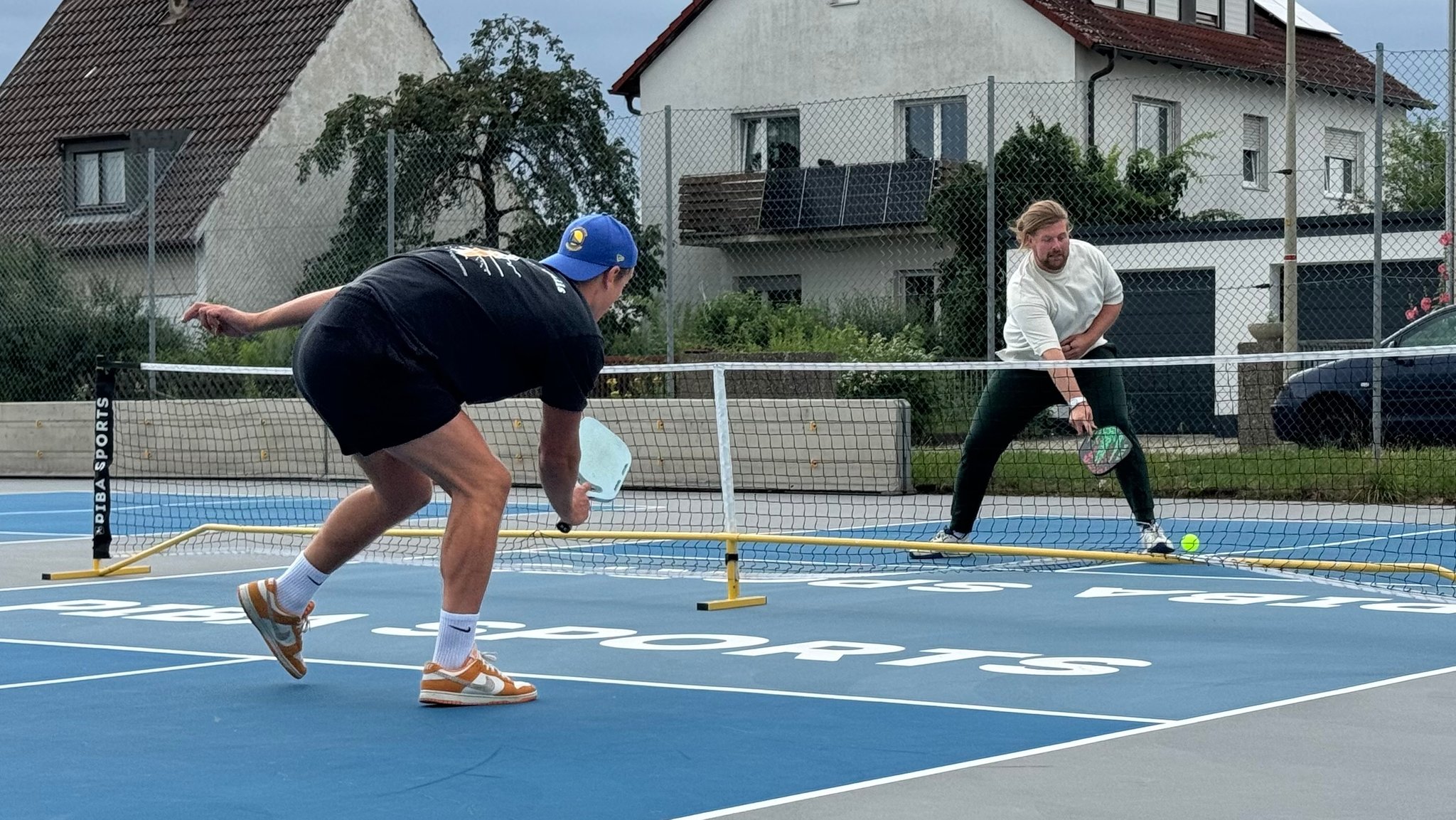 Zwei Männer spielen auf einem Platz Pickleball. 