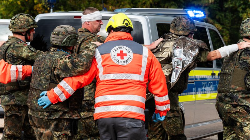 Auf dem Bild sind Sanitäter und Soldaten zu sehen, die eine verletzte Person abtransportieren. | Bild: picture alliance / CHROMORANGE | Michael Bihlmayer Auf dem Bild sind Sanitäter und Soldaten zu sehen, die eine verletzte Person abtransportieren.