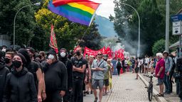 26.06.2022, Bayern, Garmisch-Partenkirchen: Schwarz gekleidete Demonstranten schwenken während der Demonstration gegen den G7 Gipfel die Gay Pride Flagge.  | Bild:dpa-Bildfunk/Daniel Vogl