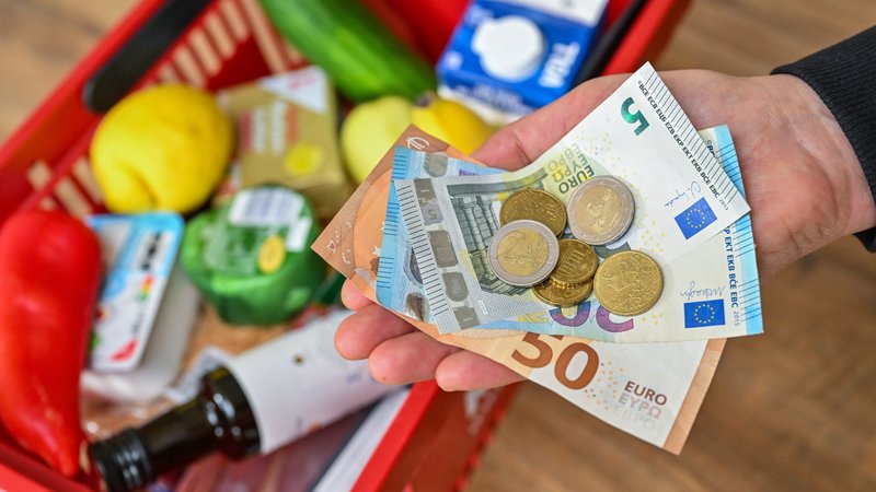  Eine Frau hält auf ihrer Hand Geld vor einem vollen Einkaufskorb mit Lebensmitteln. Das Statistisches Bundesamt gibt Inflationsrate für April 2024 bekannt.