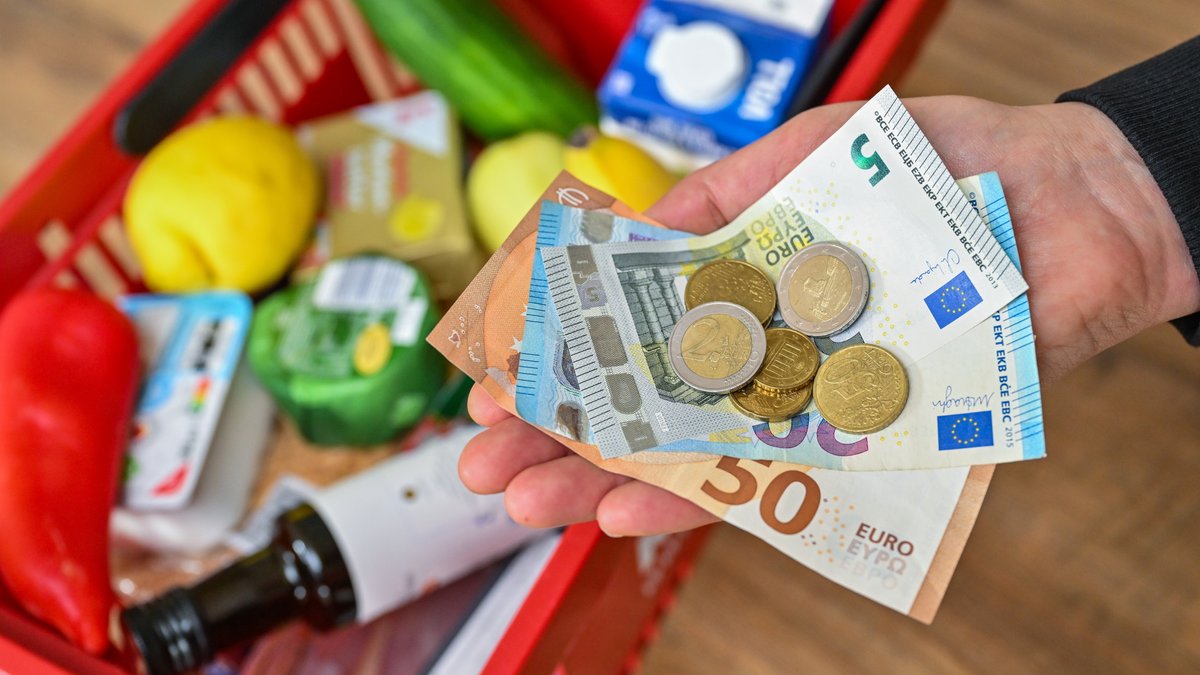  Eine Frau hält auf ihrer Hand Geld vor einem vollen Einkaufskorb mit Lebensmitteln. Das Statistisches Bundesamt gibt Inflationsrate für April 2024 bekannt.