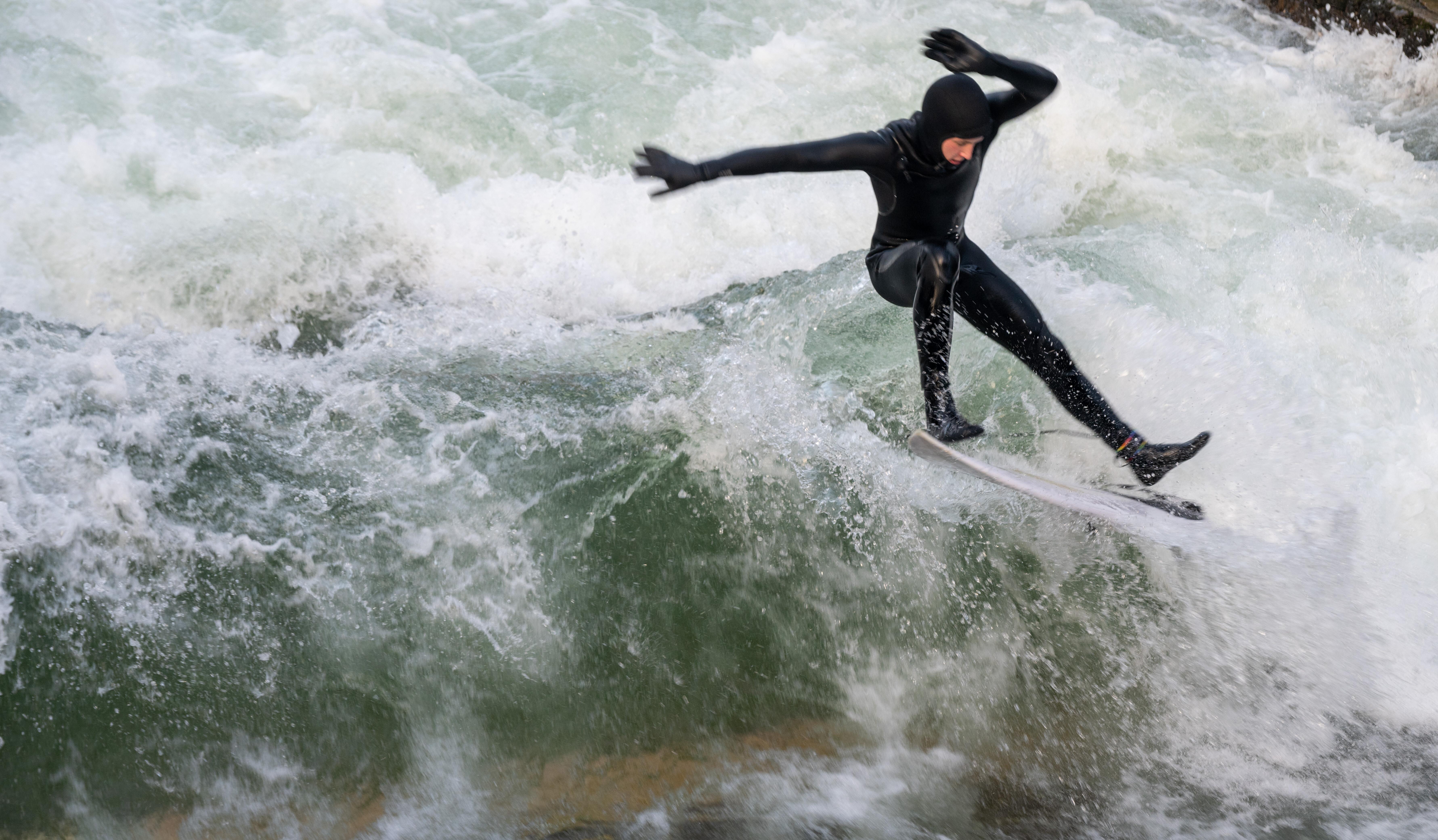 Ein Surfer surft auf der Eisbachwelle in München. 