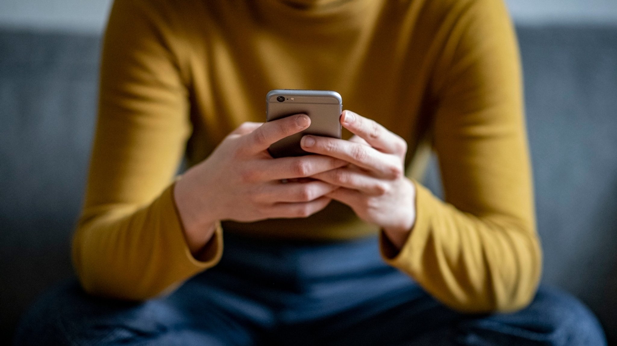 Eine junge Frau hält ein Smartphone in der Hand (Symbolbild)