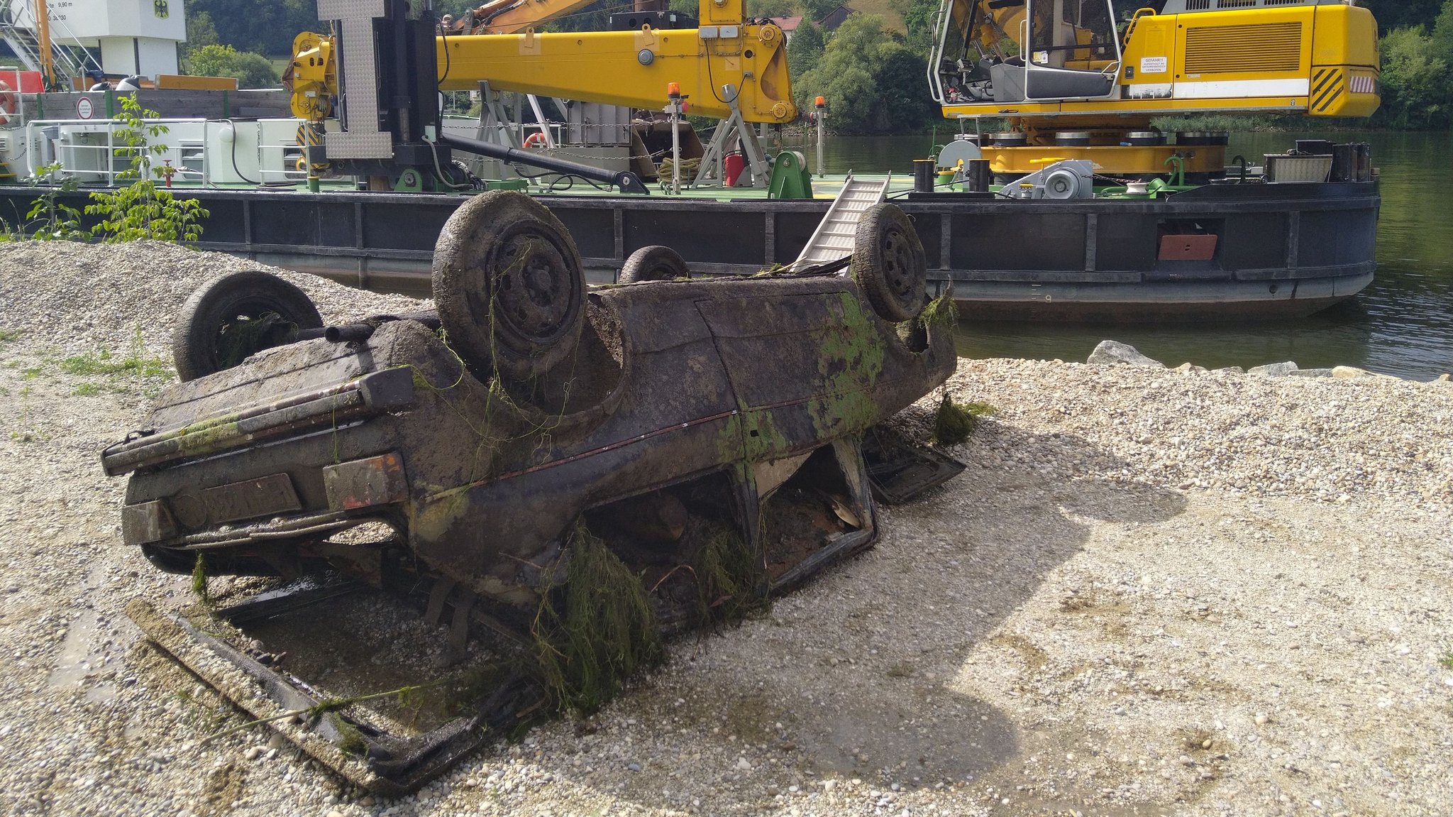 Das Wrack an Land - im Hintergrund das Boot mit Kran