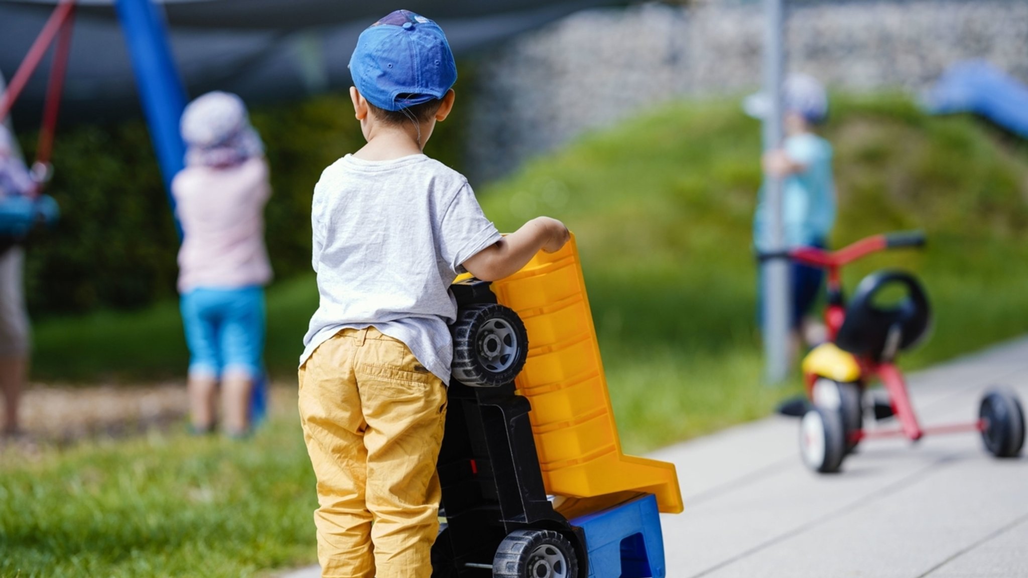 Ein Kind spielt in einer Kindertagesstätte mit einem Plastikfahrzeug. 