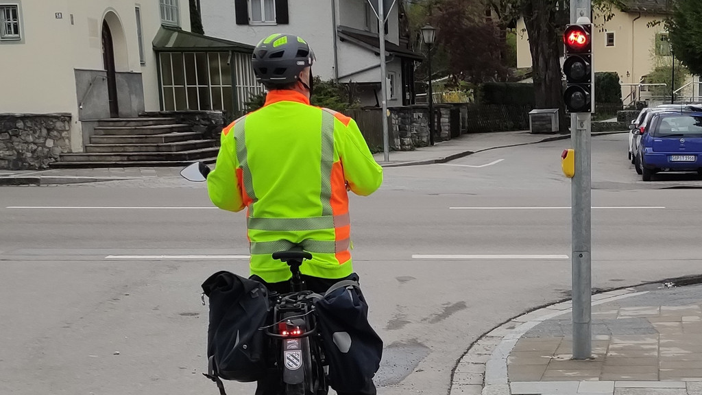 Ein Radfahrer hält an einer Fahrradampel, die zwei Meter neben dem Radweg steht