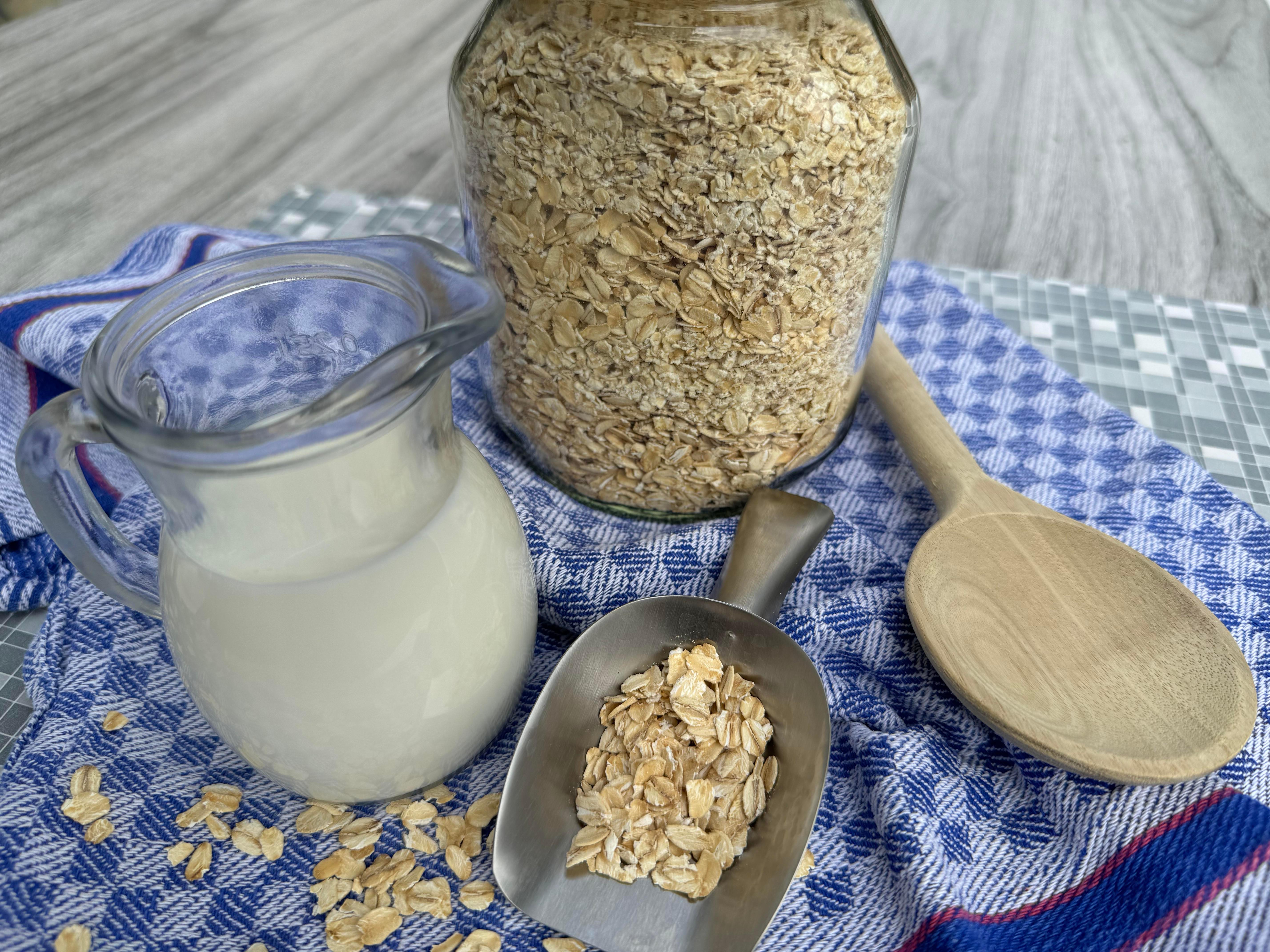 Feine und kernige Haferflocken in einem Glas zum Aufbewahren, dazu Milch für ein Müsli-Frühstück