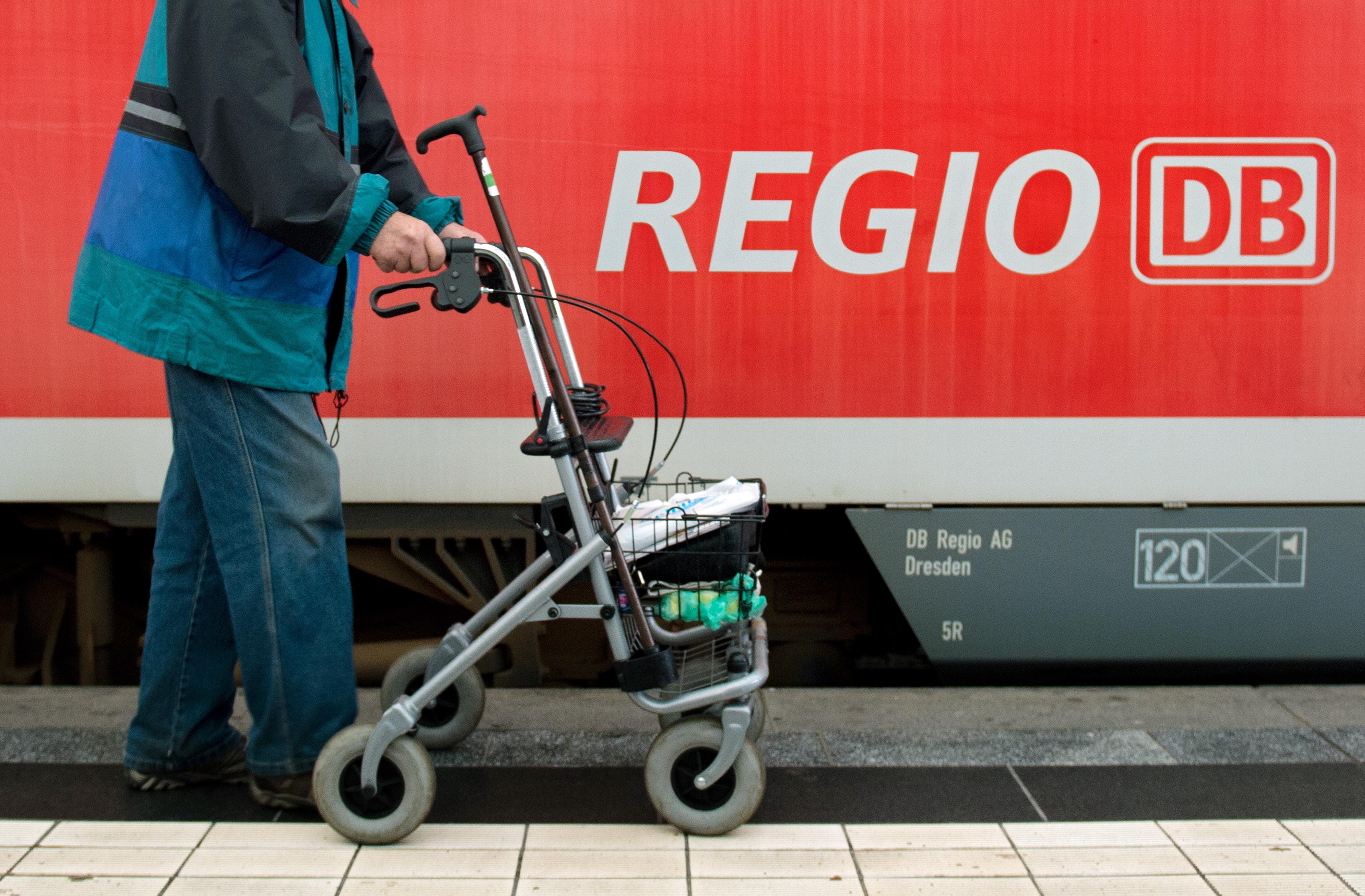 Ein Mann läuft mit seinem Rollator an einem Regionalzug der Deutschen Bahn vorbei.