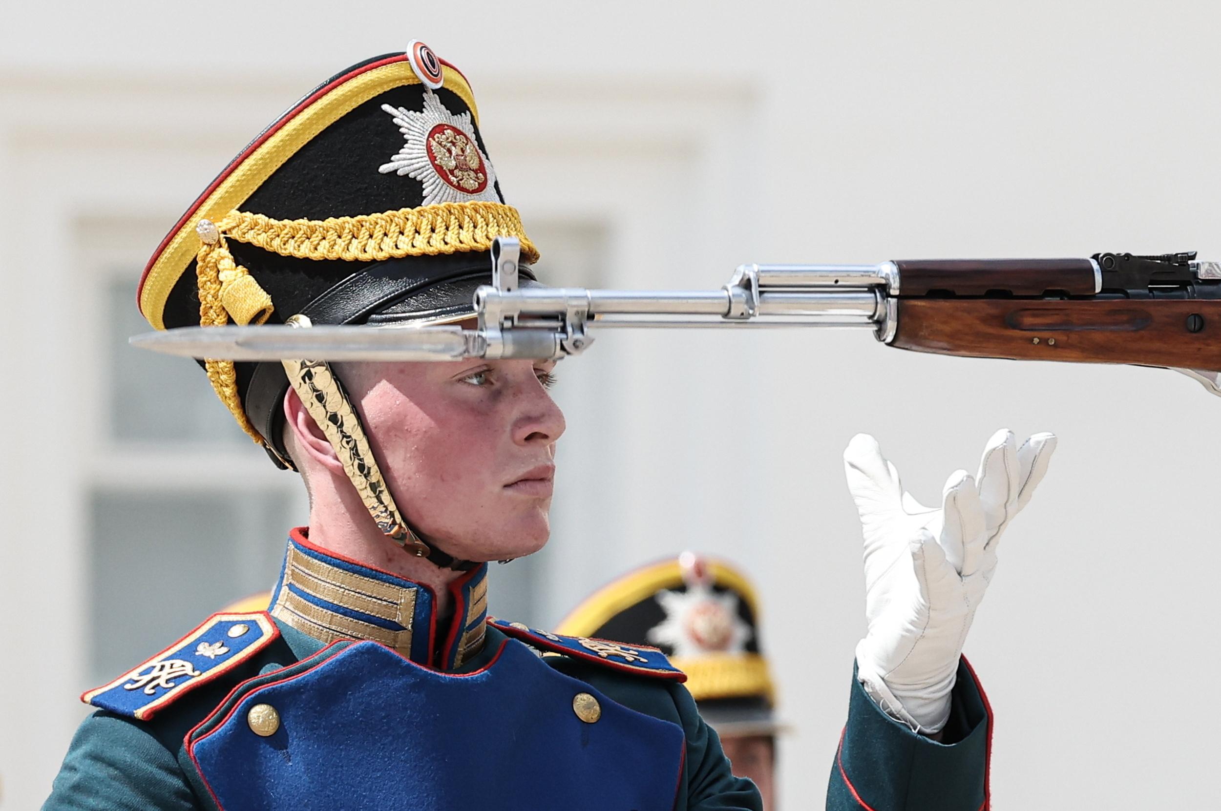 Soldat in historischer Uniform mit weißen Handschuhen hinter Gewehrlauf