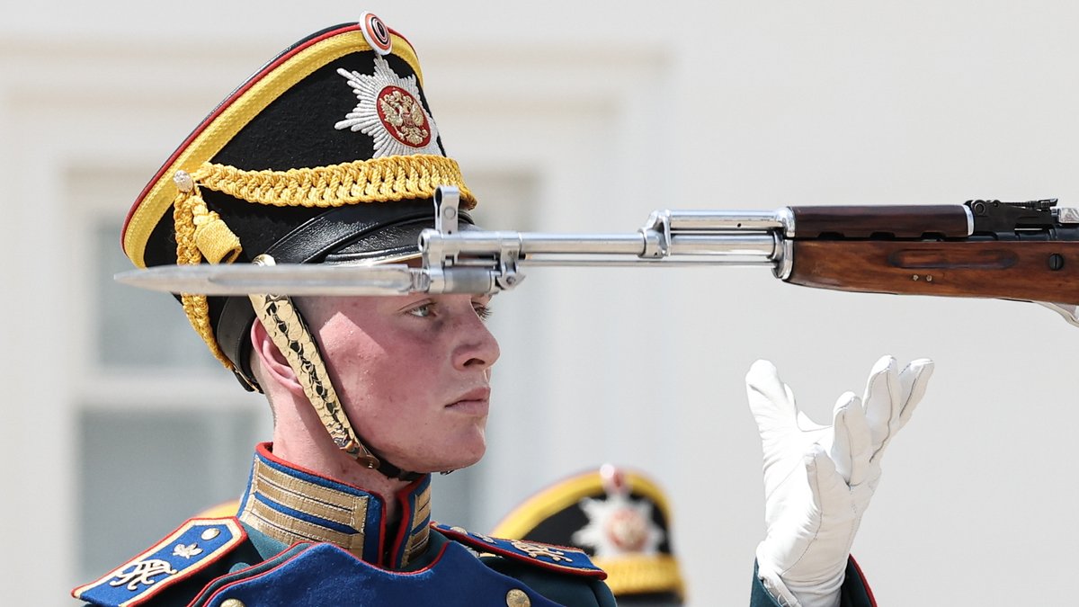 Soldat in historischer Uniform mit weißen Handschuhen hinter Gewehrlauf