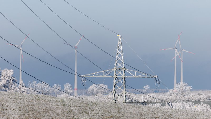 Windkraftanlagen sind am 31.12.2024 hinter einer Hochspannungsleitung nahe der Stadt Hof zu sehen. | Bild: picture alliance / dpa | Matthias Balk Windkraftanlagen sind am 31.12.2024 hinter einer Hochspannungsleitung nahe der Stadt Hof zu sehen.