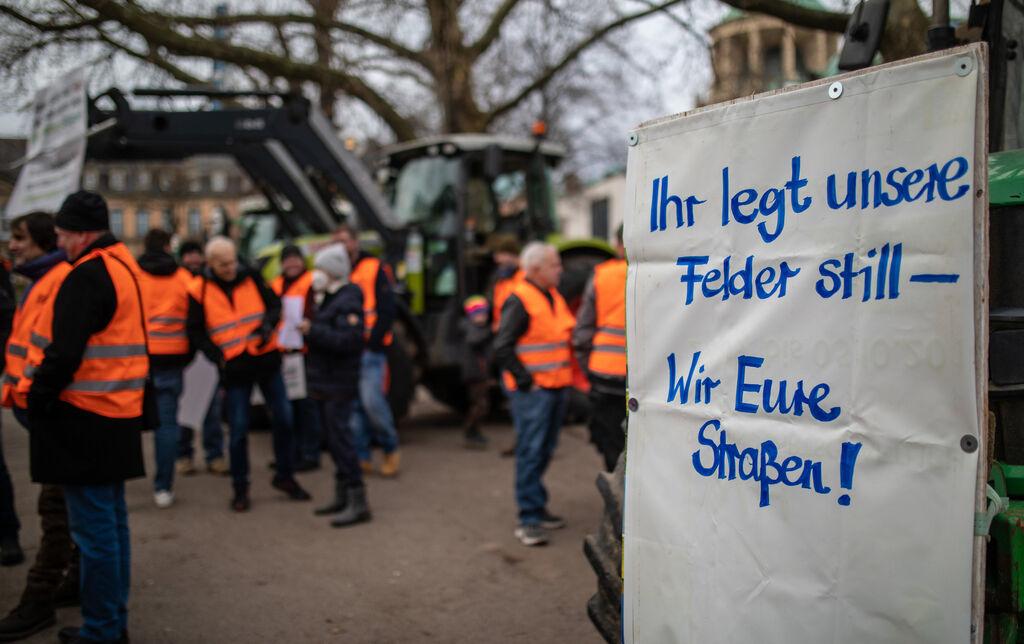 06.01.2024, Baden-Württemberg, Stuttgart: Bei einer Mahnwache vom Landesbauernverband  Baden-Württemberg, hängt ein Schild mit der Aufschrift "·Ihr legt unsere Felder still - Wir eure Straßen·" an einem Traktor. Die Mahnwache fand bezüglich des traditionellen Dreikönigstreffens der FDP in Stuttgart statt. Aus Protest gegen Kürzungen im Agrarbereich wollen die Bauern am 08.01.2024 bundesweit auf die Straße gehen. Foto: Christoph Schmidt/dpa +++ dpa-Bildfunk +++