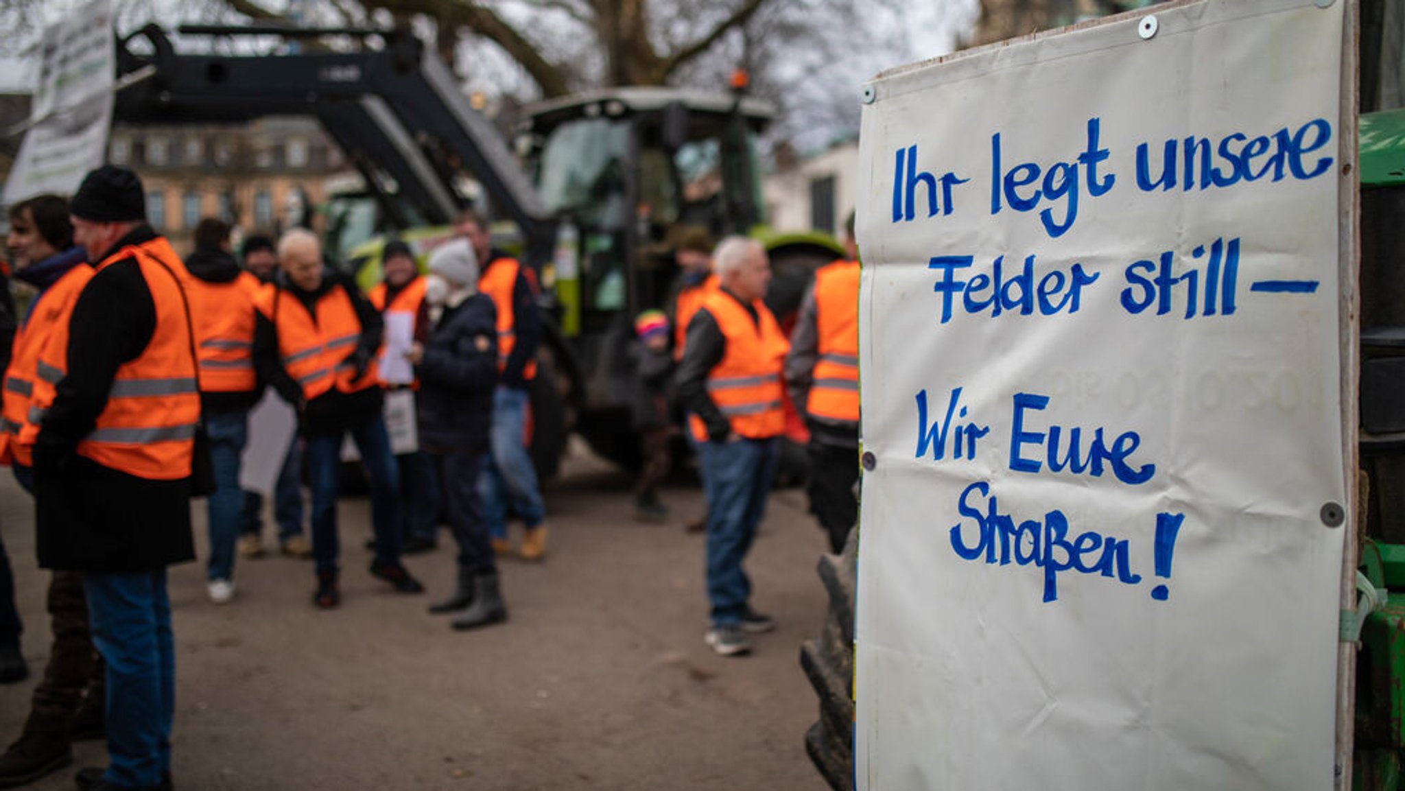 06.01.2024, Baden-Württemberg, Stuttgart: Bei einer Mahnwache vom Landesbauernverband  Baden-Württemberg, hängt ein Schild mit der Aufschrift "·Ihr legt unsere Felder still - Wir eure Straßen·" an einem Traktor. Die Mahnwache fand bezüglich des traditionellen Dreikönigstreffens der FDP in Stuttgart statt. Aus Protest gegen Kürzungen im Agrarbereich wollen die Bauern am 08.01.2024 bundesweit auf die Straße gehen. Foto: Christoph Schmidt/dpa +++ dpa-Bildfunk +++