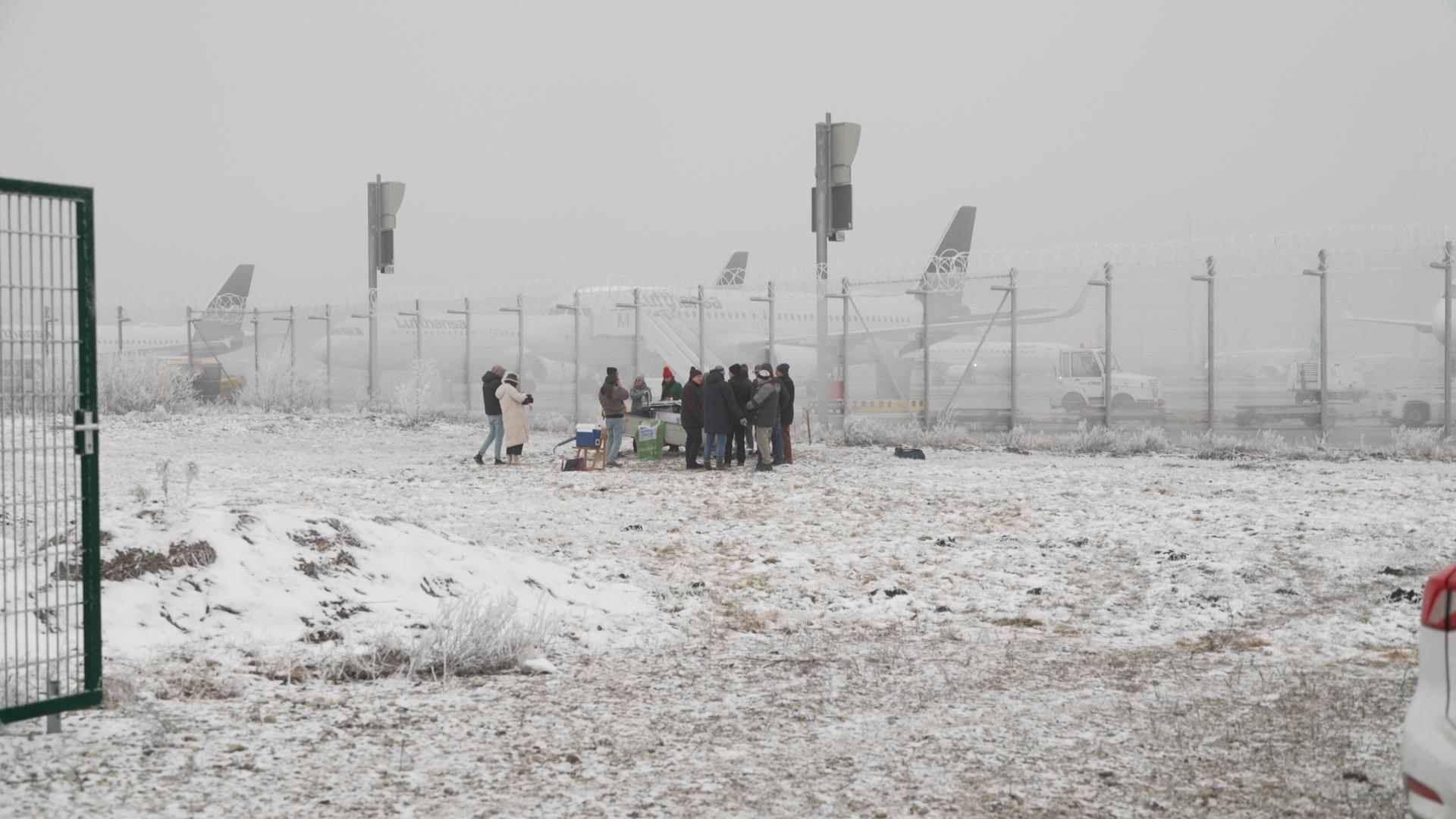 Mitglieder des Freisinger Vereins stehen um eine selbstgebaute Messstation, die sie direkt am Münchner Airport aufgestellt haben.  