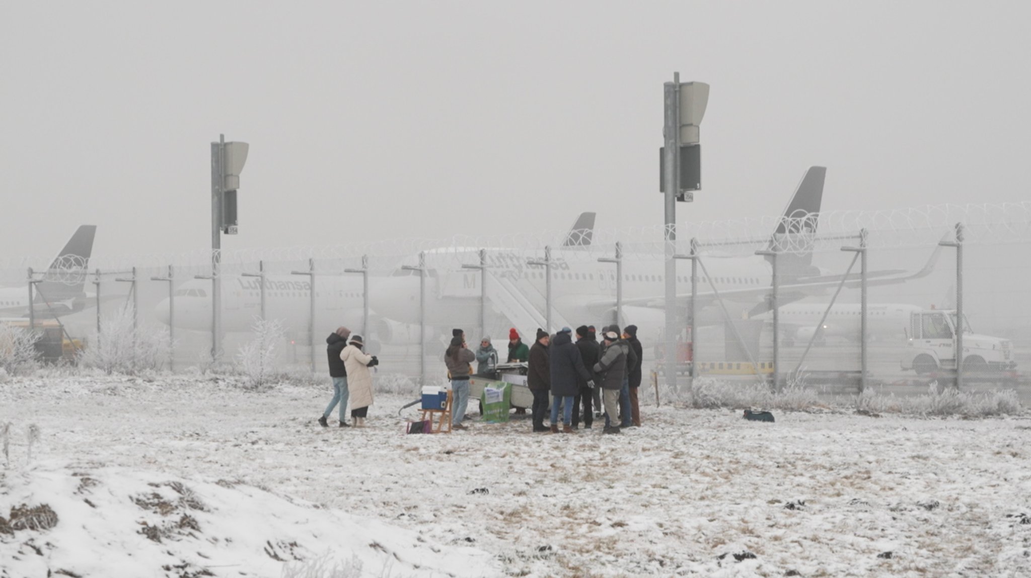 Mitglieder des Freisinger Vereins stehen um eine selbstgebaute Messstation, die sie direkt am Münchner Airport aufgestellt haben.  