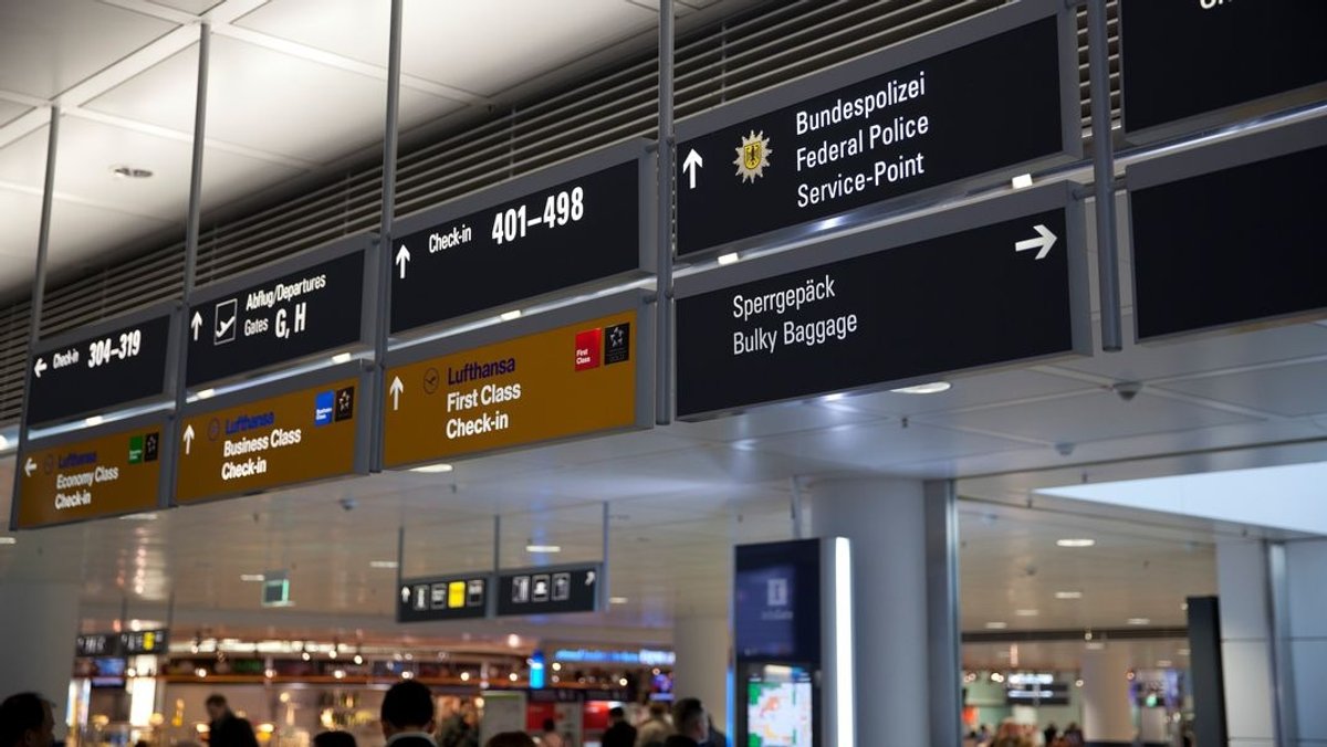 Schilder am Münchner Flughafen weisen auf Check-In-Schalter und Polizeidiensstellen hin