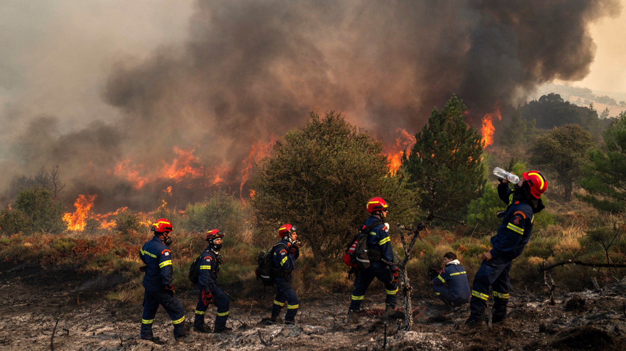 01.10.2024, Griechenland, Sofiana: Ein Feuerwehrmann trinkt Wasser in dem Dorf Sofiana, etwa 142 Kilometer westlich von Athen, am dritten Tag eines großen Flächenbrands.