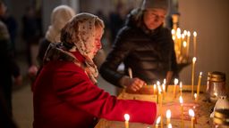 Zwei Frauen entzünden Kerzen in einer Kirche in der Ukraine. | Bild:dpa-Bildfunk/Emilio Morenatti