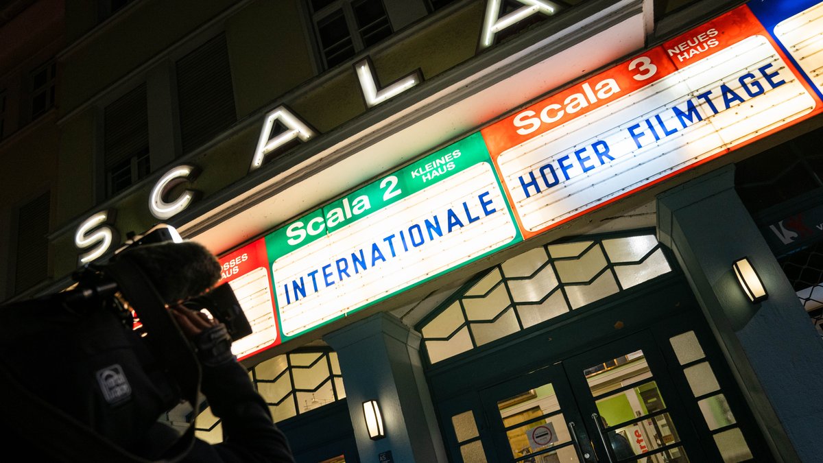 Das Kino "Scala" in Hof von außen. Ein Kamermann filmt die Anzeigetafeln davor. Dort steht: "Internationale Hofer Filmtage". 