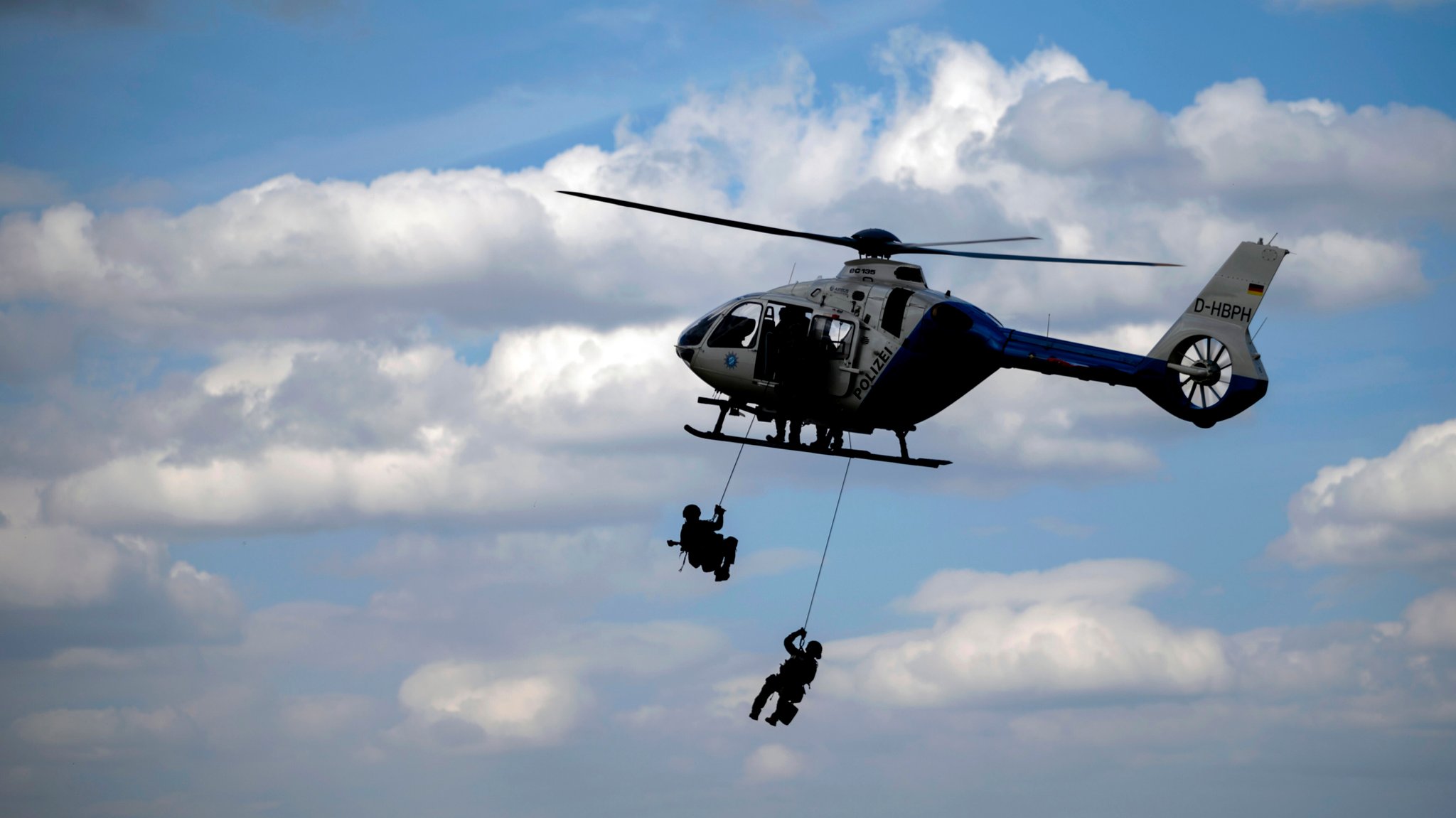 Zwei Polizisten seilen sich aus einem fliegenden Hubschrauber der bayerischen Polizei ab. (Symbolbild)