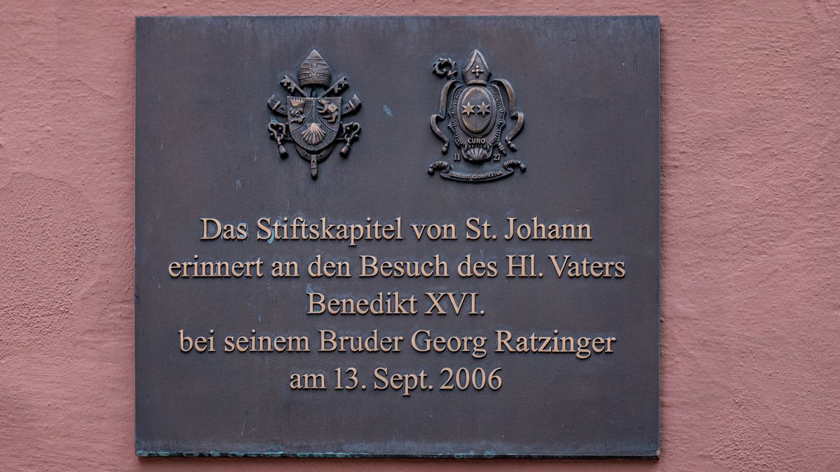 Ein Schild mit der Aufschrift "Das Stiftskapitel von St. Johann erinnert an den Besuch des Hl. Vaters Benedikt XVI. bei seinem Bruder Georg Ratzinger am 13. Sept. 2006" hängt am ehemaligen Wohnhaus von Georg Ratzinger in der Altstadt. 
