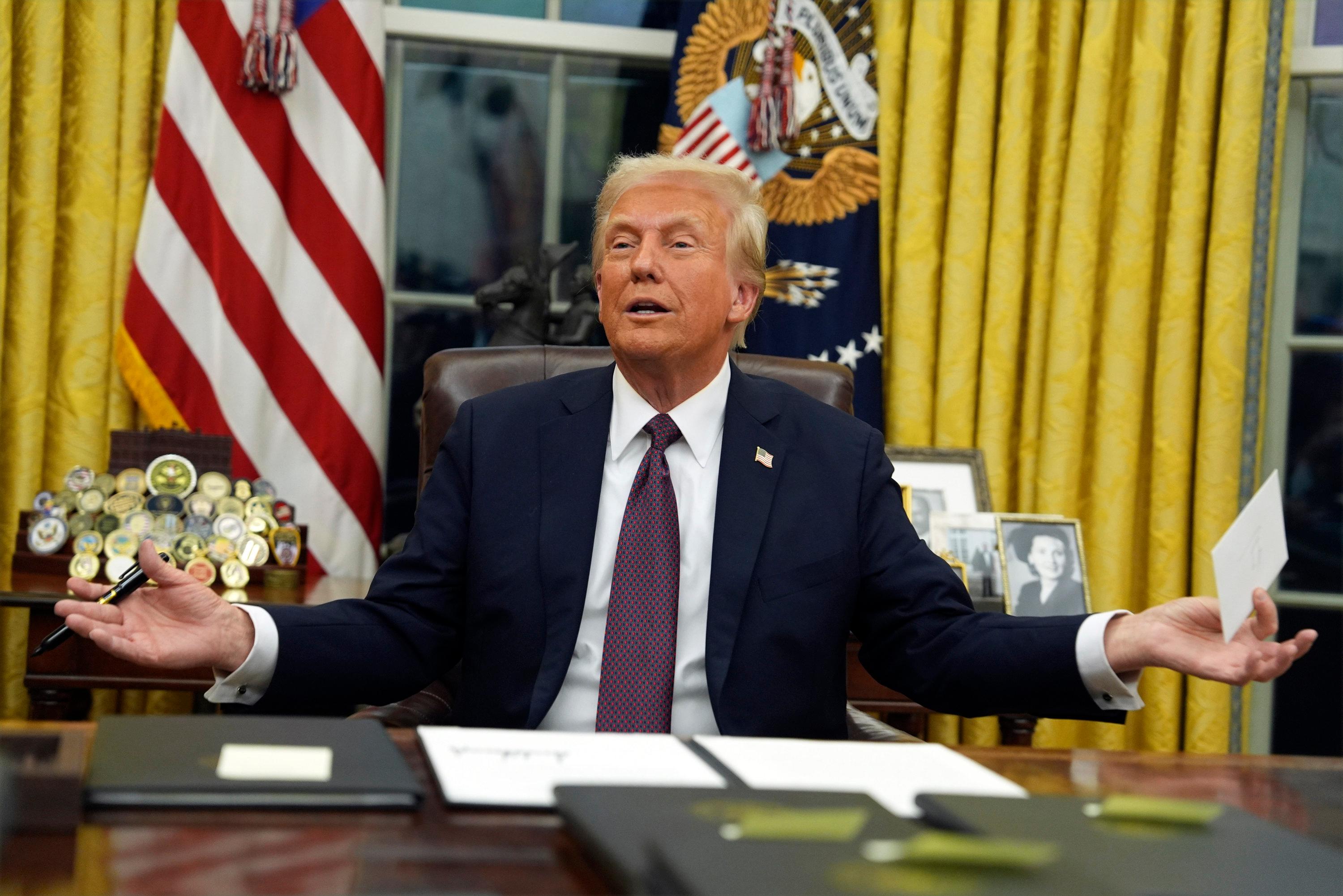 20.01.2025, USA, Washington: US-Präsident Donald Trump hält den Brief hoch, den der ehemalige US-Präsident Biden für ihn im Schreibtisch hinterlassen hat, während er im Oval Office des Weißen Hauses Anordnungen unterzeichnet.