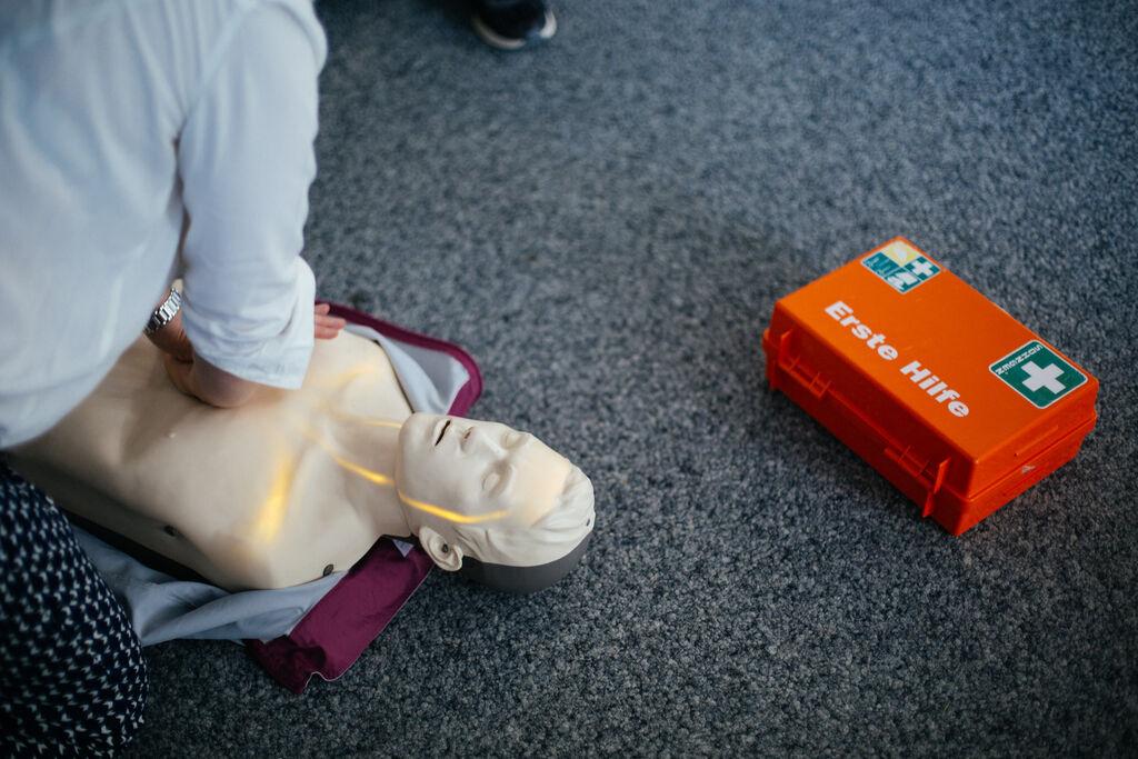 Eine Person übt die Herzdruckmassage an einer Puppe.