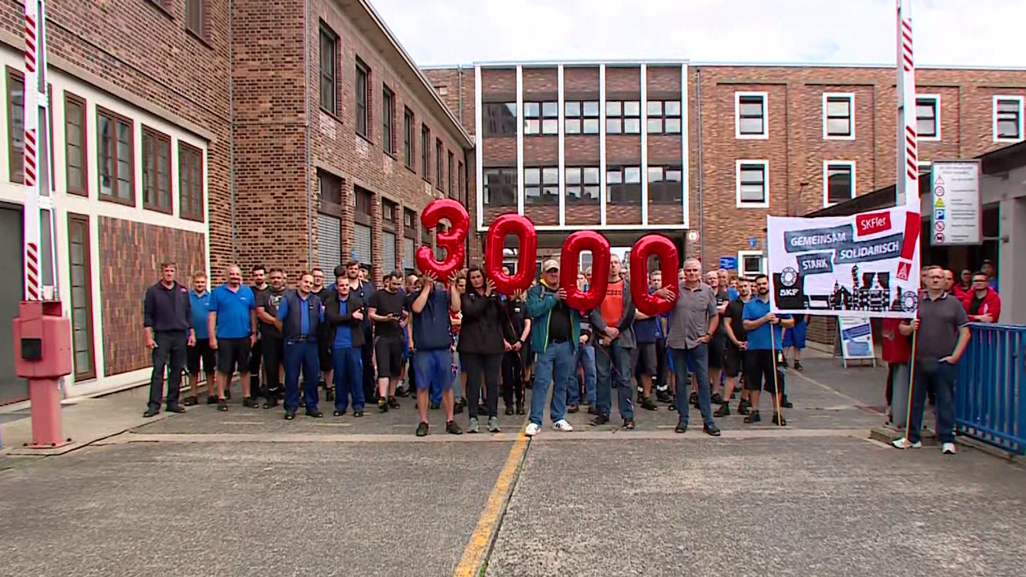 Mitarbeiter von SKF haben sich vor dem Werk in Schweinfurt zu einer Demonstration versammelt und halten Luftballons mit der Zahl 3.000 hoch.