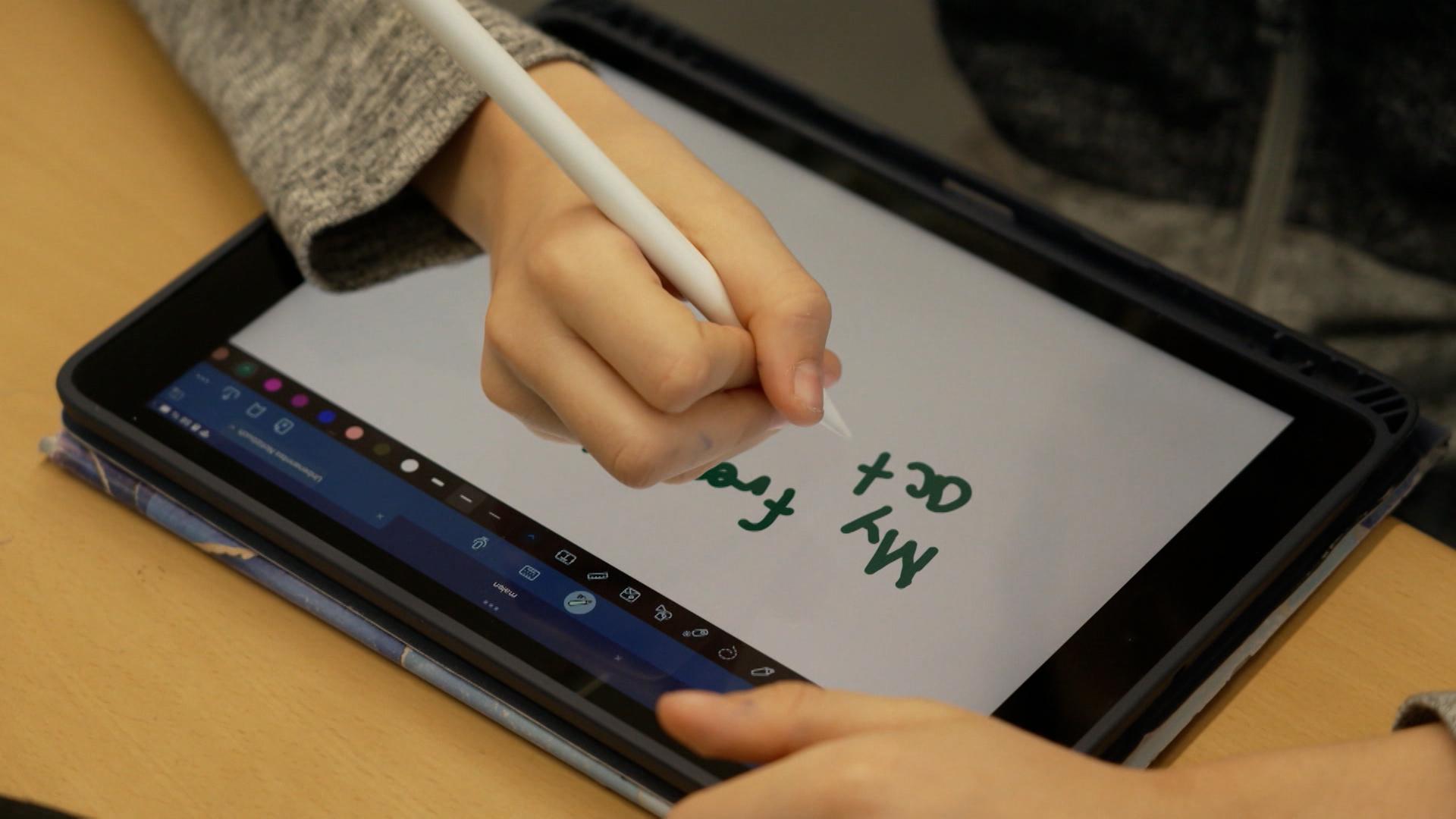 Ein Schüler notiert sich etwas auf einem Tablet-Computer.