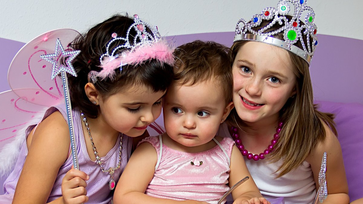 Drei Kinder auf dem Sofa mit Prinzessinnen- und Feenverkleidung