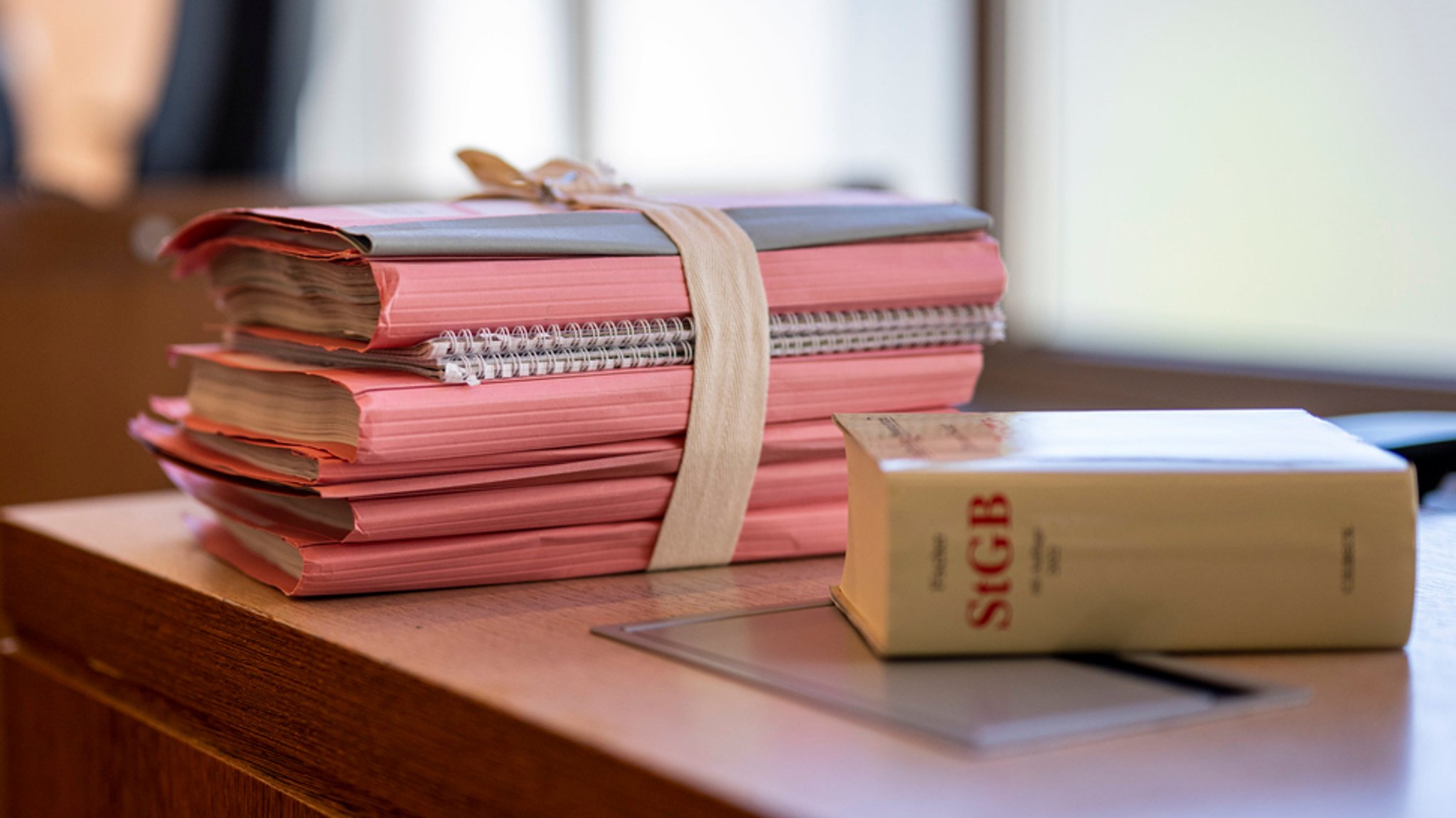 Aktenordner und das Strafgesetzbuch liegen in einem Gerichtssaal auf dem Tisch der Staatsanwaltschaft (Symbolbild).