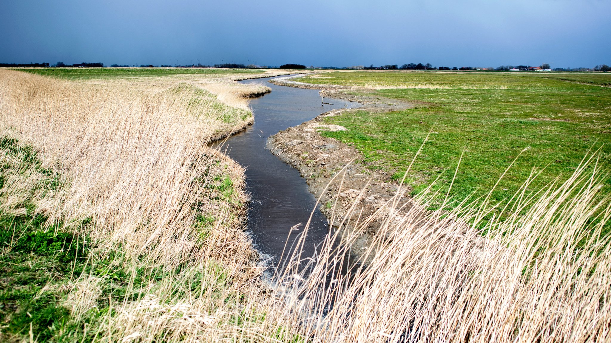 Ein kleiner Fluss schlängelt sich durch Wiesen und Felder.