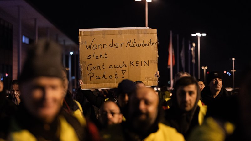ARCHIV (12.12.2023) - Symbolbild für Streik in der Logistikbranche. Streikende von UPS und Fedex stehen bei einem Warnstreik auf einem Parkplatz am Flughafen Köln/Bonn. | Bild: picture alliance/dpa | Rolf Vennenbernd ARCHIV (12.12.2023) - Symbolbild für Streik in der Logistikbranche. Streikende von UPS und Fedex stehen bei einem Warnstreik auf einem Parkplatz am Flughafen Köln/Bonn.