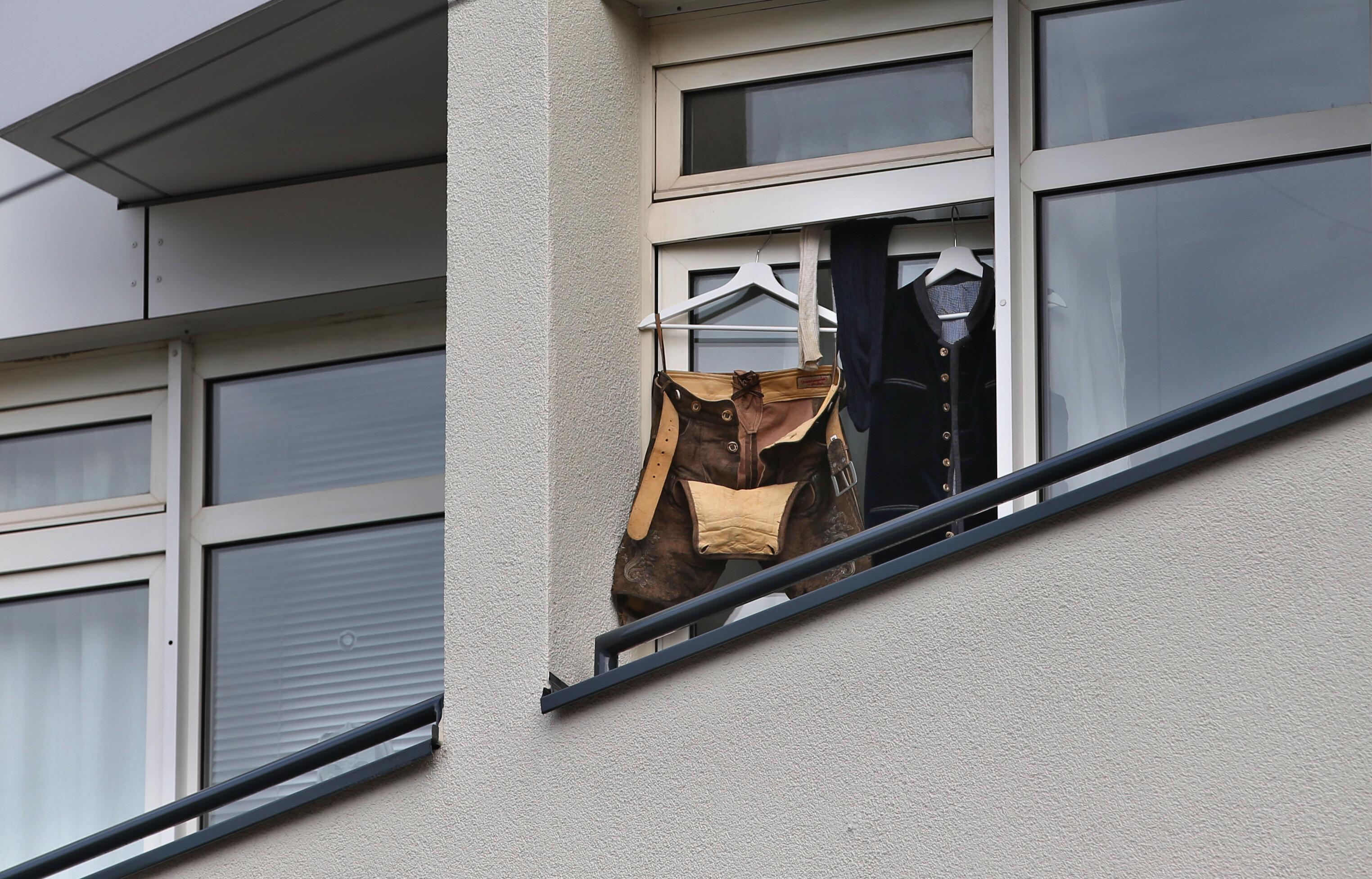 Eine Lederhose und eine Trachtenweste hängen während der Wiesn-Zeit an der Balkontüre einer Wohnung in München zum Auslüften.