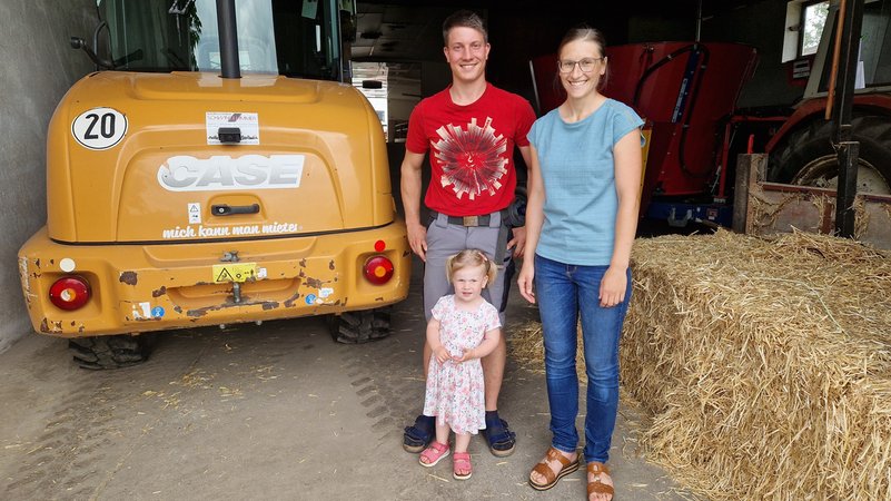 Theresa und Stefan Bloos vor dem Hoflader mit ihrer zweijährigen Tochter Elisabeth. | Bild: BR/Stefanie Heiß Theresa und Stefan Bloos vor dem Hoflader mit ihrer zweijährigen Tochter Elisabeth.