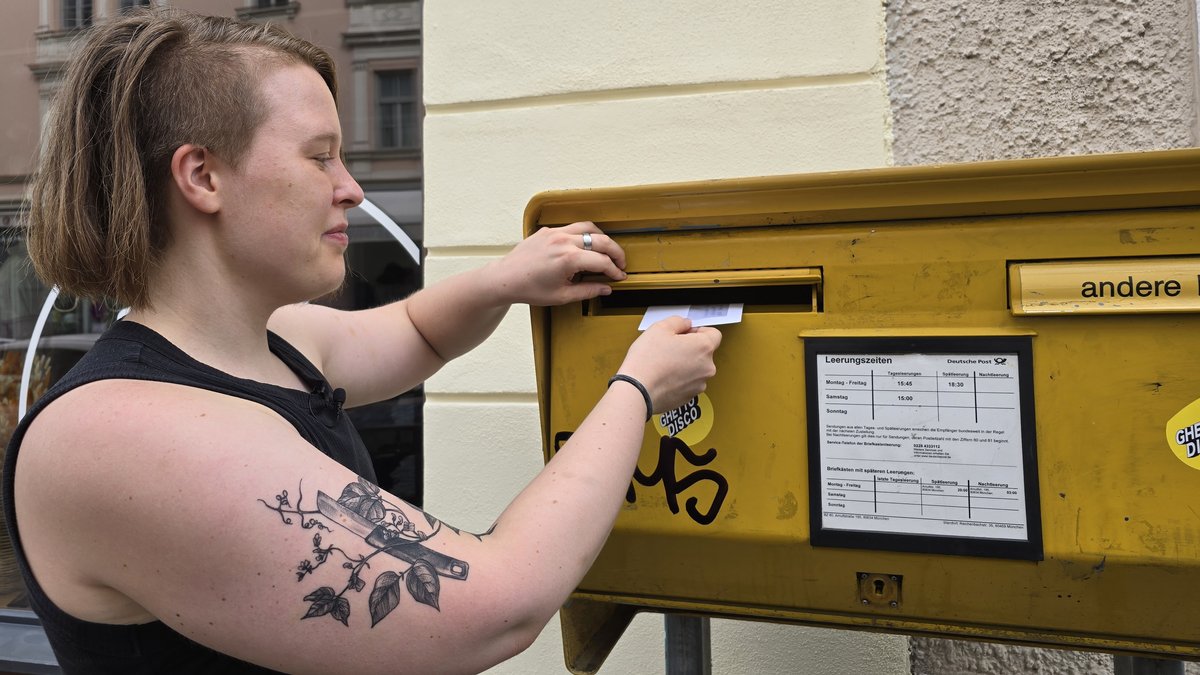 Eine Person wirft einen Brief in den Briefkasten.